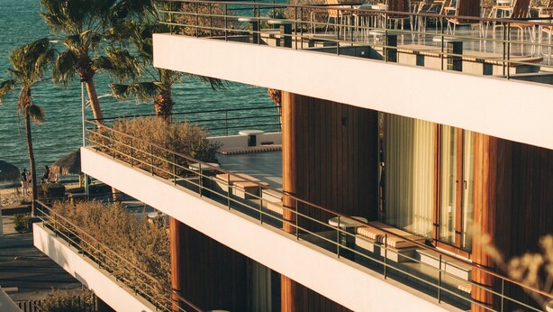 A modern building with a balcony overlooking the sea, featuring outdoor seating and palm trees. - Baja Club Hotel, La Paz, Baja California Sur, a Member of Design Hotels (La Paz)