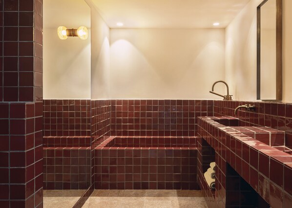 Un baño con piso de baldosas, lavamanos, espejo e iluminación.