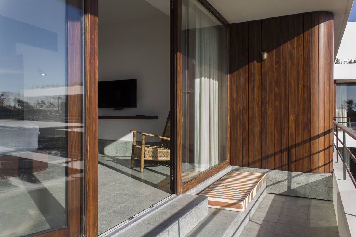A modern interior with a wooden wall, a glass door, a flat-screen TV, and a wicker chair.