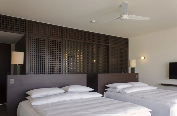 Una habitación de hotel con dos camas, un ventilador de techo y un ventanal con vistas.