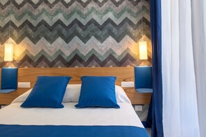 A hotel room with a wooden headboard, two blue pillows, a zigzag patterned wall, and two wall-mounted lamps. - Bright&Modern Suite in Sorrento Old Town (Sorrento)