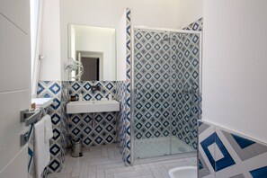 A bathroom with a white sink, mirror, and shower enclosure with patterned tiles. - Bright&Modern Suite in Sorrento Old Town (Sorrento)
