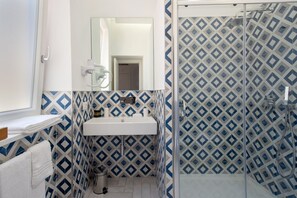 A bathroom with a white sink, a mirror above it, and a shower area with a patterned tile wall. - Bright&Modern Suite in Sorrento Old Town (Sorrento)