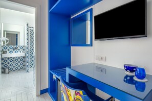 Un baño moderno con una decoración azul y blanca, cabina de ducha de vidrio y televisión montada.