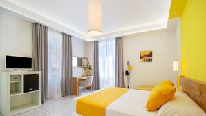 Ein Hotelzimmer mit Bett, Schreibtisch, Fernseher und Stuhl.