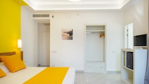 Quarto de hotel com cama, armário, televisão e zona de duche.