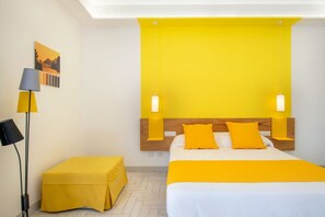 Ein Hotelzimmer mit einem Bett, einem Nachttisch, einer Lampe und einem Bild an der Wand.