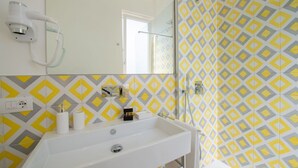 Une salle de bain avec un lavabo blanc, un miroir et un espace douche.
