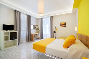 Ein Hotelzimmer mit Bett, Schreibtisch, Fernseher und Stuhl.