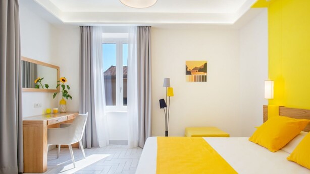 Ein Hotelzimmer mit Bett, Schreibtisch, Stuhl, Lampe und Fenster.