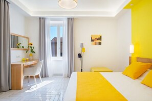 Une chambre d’hôtel avec un lit, un bureau, une chaise, une lampe et une fenêtre.