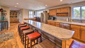 A spacious kitchen with a large island, wooden cabinets, and a view of the outdoors. - Riverfront Coastal Escape with Deep Water Dock! (Westport Island)