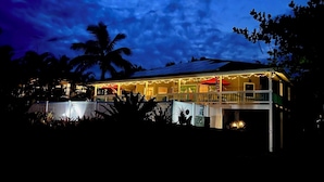 A two-story house with a balcony, string lights, and an American flag.