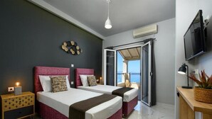 Ein Hotelzimmer mit zwei Betten, einem Fernseher, einem Schreibtisch und einem Balkon mit Blick.