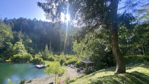 A serene lakeside setting with a wooden deck, lounge chairs, and a small pavilion. - Hidden Pond Gong Suite - Luxury , Pet Friendly, with Hot Tub and Private Beach  (Victoria)