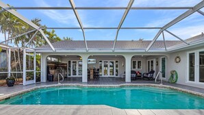 A swimming pool with a covered patio area, a bar, and outdoor seating. - Private Beach, Heated Pool, Kayaks, & Pool Table - Villa Las Palmas - Roelens Vacations (Cape Coral)