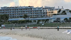 A beachfront hotel with multiple balconies, a sandy beach, and a clear sky. - Maho Royal Islander, La Terrasse 2br 2ba Beautiful White Sand Beach (Lowlands)