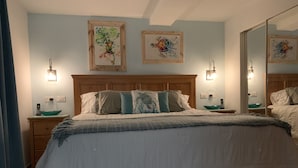 A bedroom with a wooden bed, white bedding, two bedside tables with lamps, and artwork on the walls. - Maho Royal Islander, La Terrasse 2br 2ba Beautiful White Sand Beach (Lowlands)