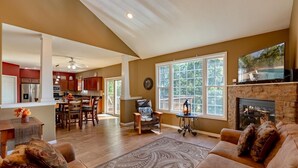 A spacious living room with a fireplace, a dining area, and a kitchen with wooden cabinets. - Private pool, boat rental, hiking and enjoying all the great restaurants in the area. (Lake Ozark)