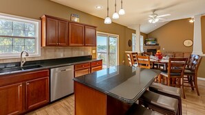 A spacious kitchen with wooden cabinets, a black countertop, and a central island with stools. - Private pool, boat rental, hiking and enjoying all the great restaurants in the area. (Lake Ozark)