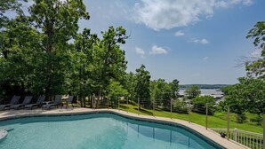 A swimming pool with a view of a lake and trees. - Private pool, boat rental, hiking and enjoying all the great restaurants in the area. (Lake Ozark)