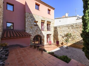 Un patio con muro de piedra, edificio rosa y suelo de baldosas.