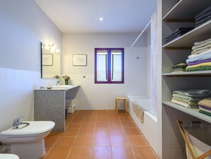 Un baño con inodoro, lavamanos y zona de ducha.