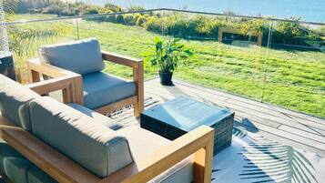 Relax in a serene outdoor seating area with a comfortable sofa, small table, and lush green surroundings.
