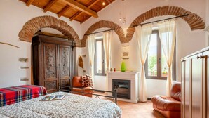 A bedroom with a fireplace, a bed, a sofa, and a wooden wardrobe. - Stunning  villa for 6 guests with WIFI and TV (Molini Di Triora)