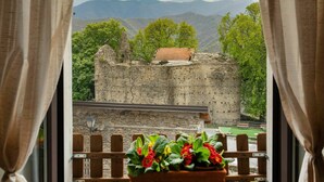 A view of a historic stone wall with a small building on top, surrounded by greenery and mountains in the background. - Stunning  villa for 6 guests with WIFI and TV (Molini Di Triora)