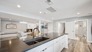 A modern kitchen with a large island, white cabinetry, and a sign reading "HALL LAKE CABINS". - Beautiful Sunrise Views of Hall Lake! (Fairmont)