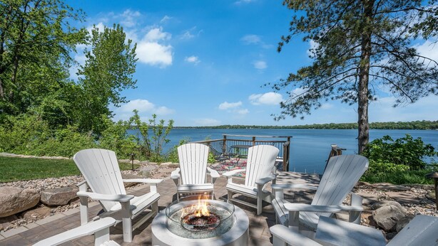 A deck with Adirondack chairs and a fire pit overlooking a lake. - Beautiful Sunrise Views of Hall Lake! (Fairmont)