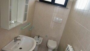 A small bathroom with a sink, bidet, toilet, and a window above the toilet. - Nice apartment for 3 people with WIFI, TV, terrace and pets allowed (Silvi)