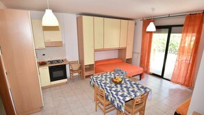 A compact room with a kitchenette, a dining area with a table and chairs, a bed, and a sliding glass door to the outside. - Nice apartment for 3 people with WIFI, TV, terrace and pets allowed (Silvi)