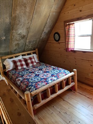 A wooden bed in a sloped ceiling room with a window and a mirror on the wall. - Cabin overlooking creek close to National Forrest a great place to relax  (Ozone)