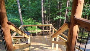 A wooden staircase leading up to a deck surrounded by trees.