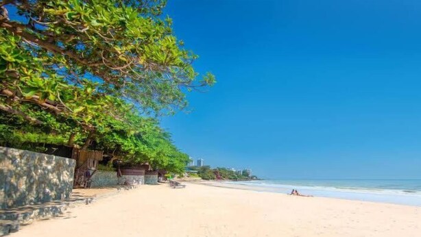 A beach with a stone wall and trees on one side, and a clear blue sky. - AnB poolvilla 2BR with private beach (Pattaya)