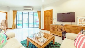A modern living room with a sofa, coffee table, TV, and a wooden cabinet. - AnB poolvilla 2BR with private beach (Pattaya)