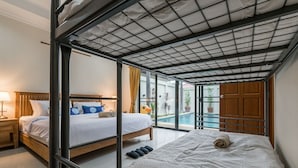 A hotel room with a bunk bed, a separate bed, a view of a swimming pool, and a wooden door. - AnB poolvilla 2BR with private beach (Pattaya)