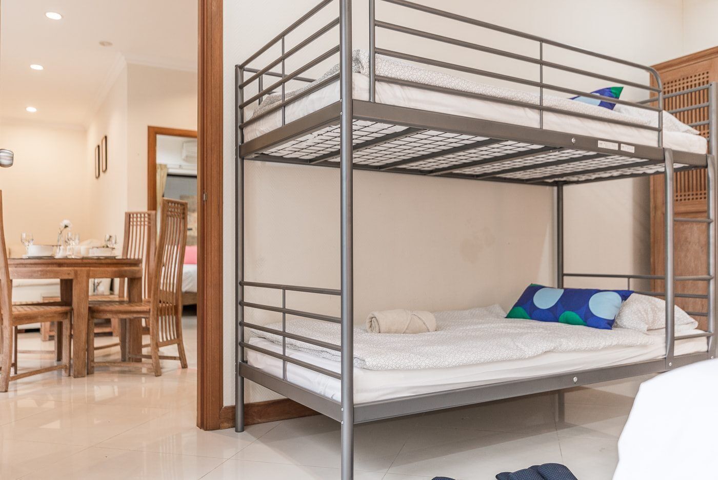 Una cama individual superpuesta con una mesa y sillas de madera en la habitación.