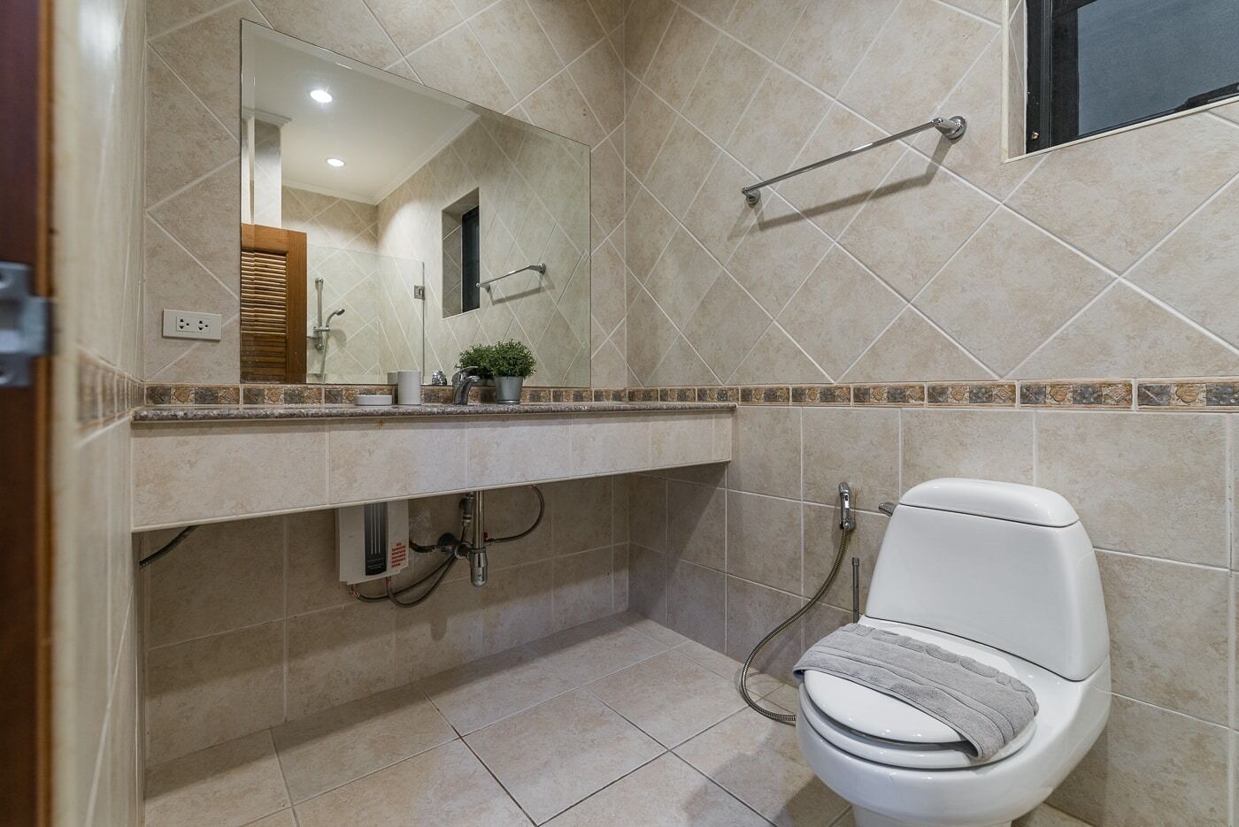 A bathroom with a toilet, a sink with a mirror, and a shower area.