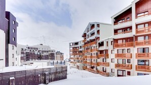 Un área urbana cubierta de nieve con edificios de varios pisos, incluyendo un hotel con balcones y un edificio moderno con fachada oscura.