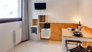 Una cocina moderna con detalles de madera, televisión integrada y un comedor con mesa y sillas.