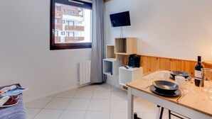 Una cocina moderna con techo de madera, un televisor montado en la pared y ventana con vista a un edificio.