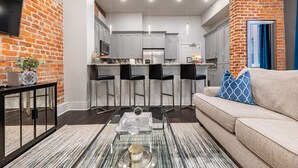 A modern kitchen with white cabinets, a stainless steel refrigerator, and a bar area with black bar stools. - ⚜️ Perfect Downtown 1 Bedroom plus Queen Sleeper Sofa & Private Terrace ⚜️ - The Livingston (New Orleans)