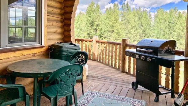 Une terrasse en bois avec un barbecue, une table et des chaises.