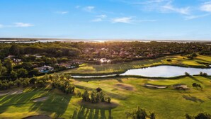 A golf course with bunkers, a pond, and houses in the background. - Albarella S3 3, Isola di Albarella, Italy (Isola di Albarella)