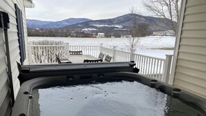 Ein Whirlpool auf einem Balkon mit Blick auf schneebedeckte Berge.