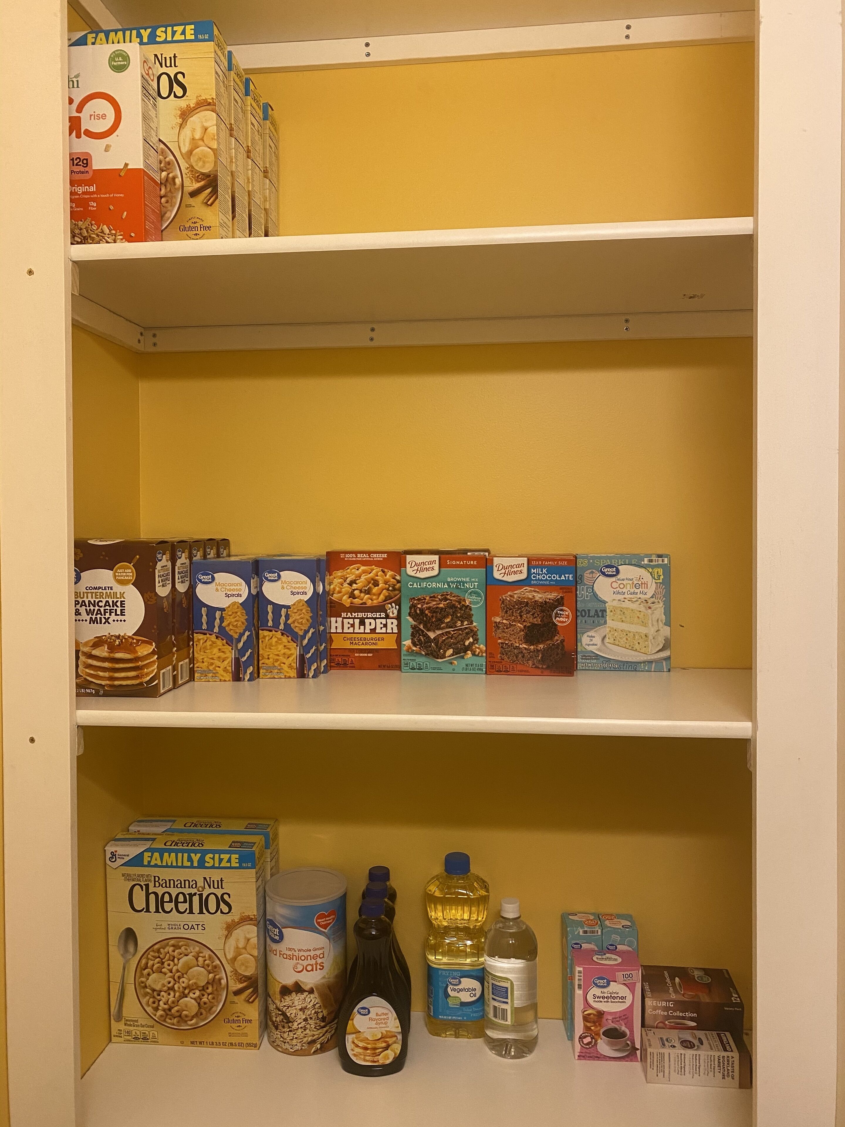 Una despensa con estantes llenos de diversos productos alimenticios, como cereales, preparados para hornear y condimentos.
