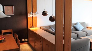 Een moderne keuken met houten kastjes, een eettafel en een hanglamp.